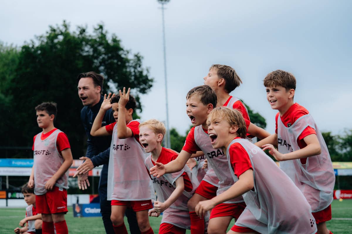 Groep enthousiaste kinderen juicht tijdens een oefenvorm van de Skills Voetbaldagen van FC VoetbalSkills.