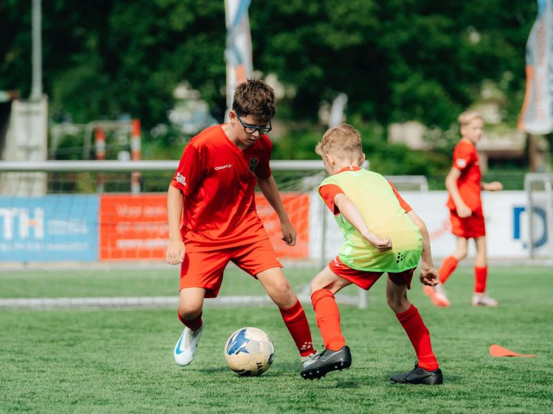 Intens duel tussen twee jonge spelers tijdens de Skills Voetbaldagen van FC VoetbalSkills.